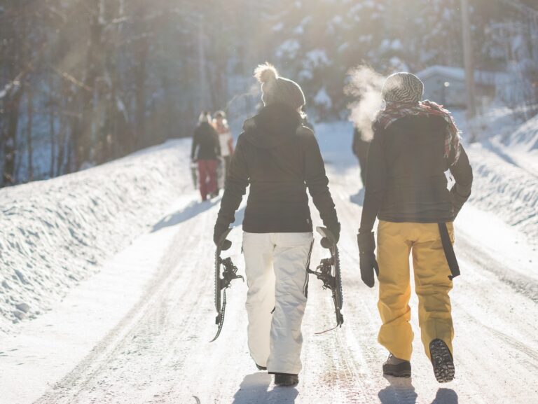 person holding snow ski blades while walking on snowy mountain during daytime